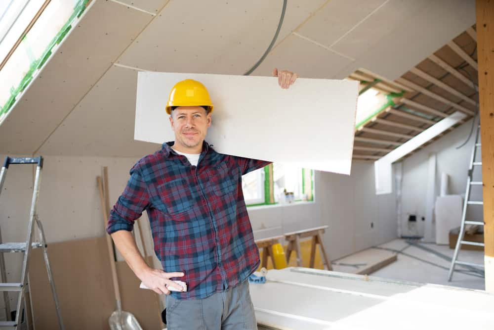 BA Construction worker holding drywall on a Pinellas County job site.